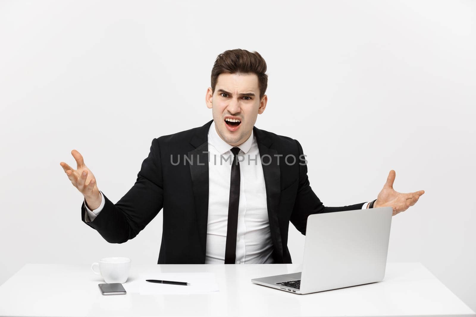 Business Concept: Portrait of screaming angry businessman sitting in office isolated over white background