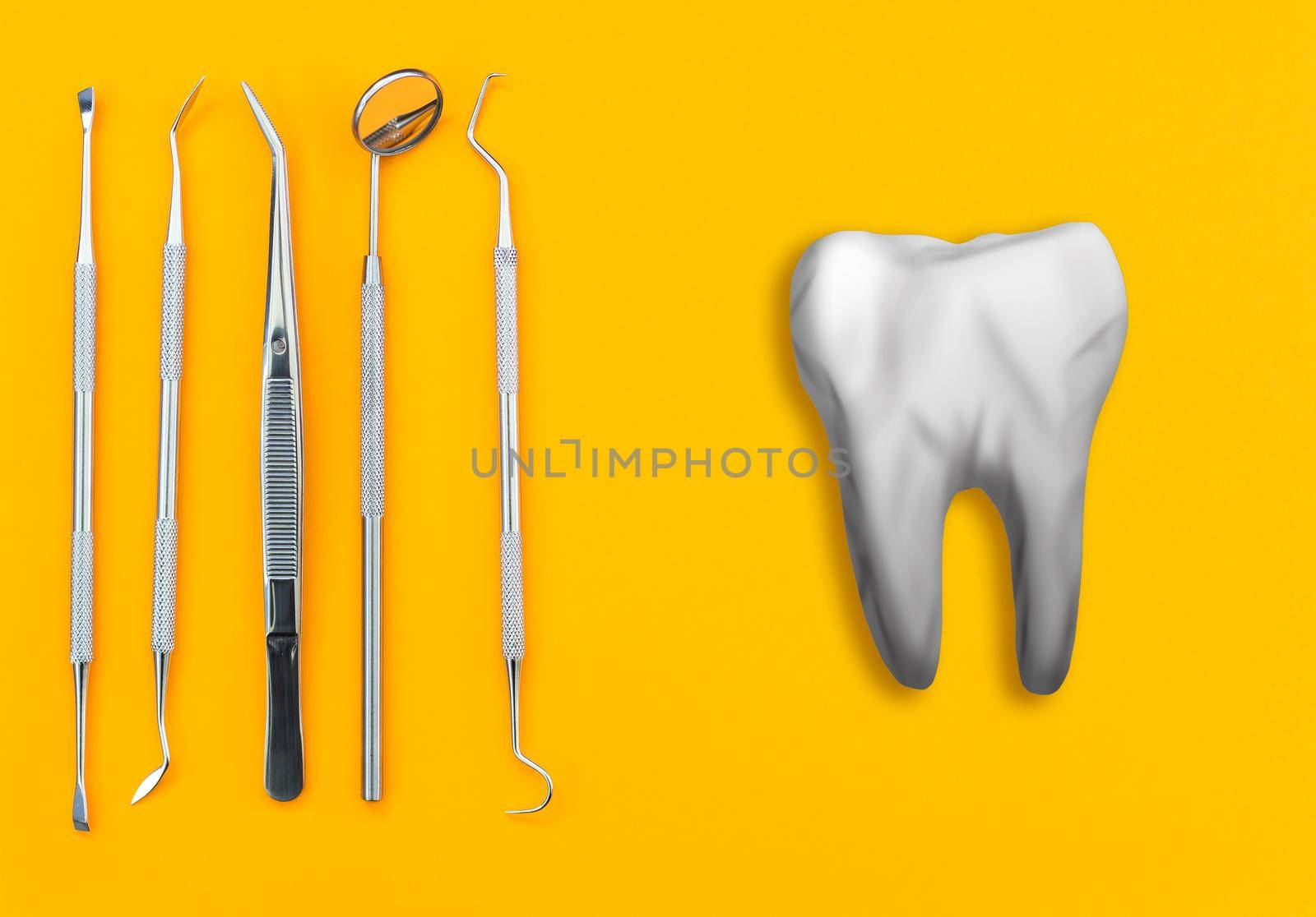 Artificial tooth and dental instrument on table. Dental services concept.
