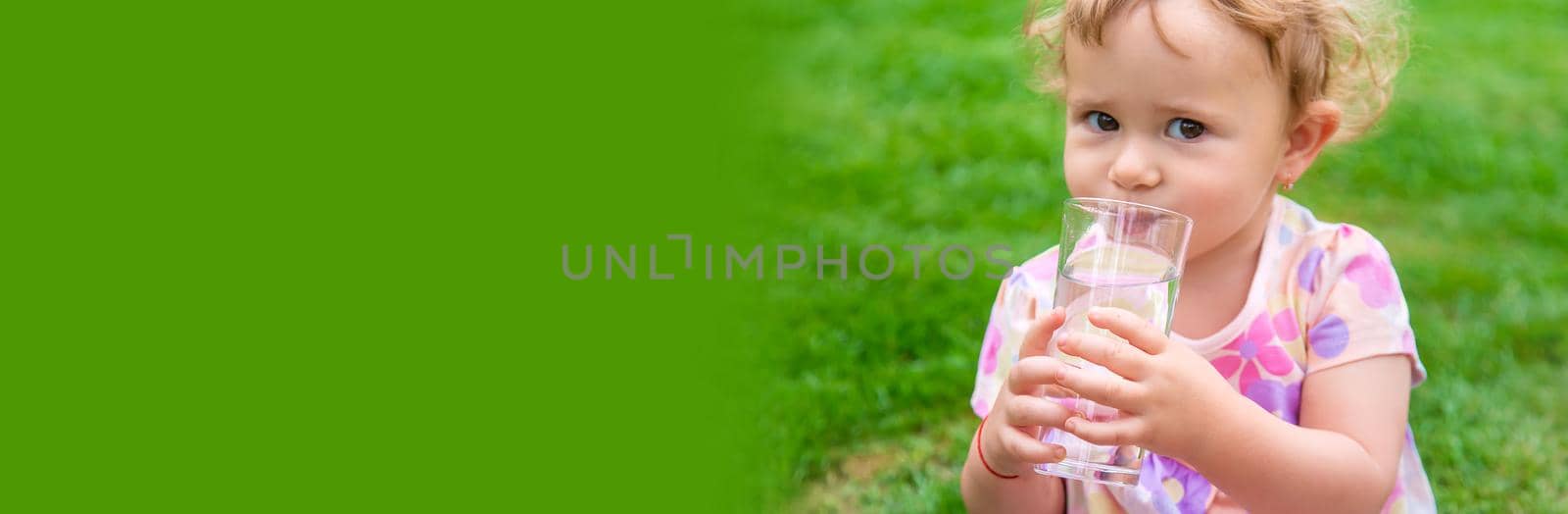 Baby drinks water from a glass. Selective focus. by yanadjana