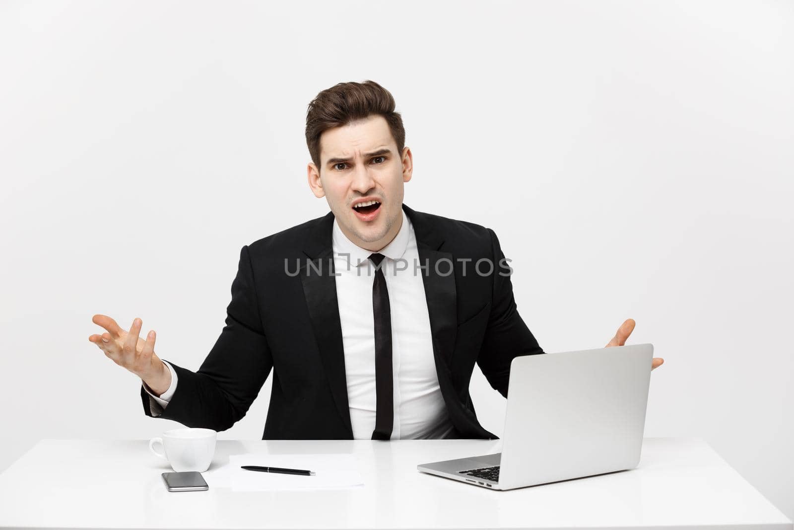 Business Concept: Portrait of screaming angry businessman sitting in office isolated over white background