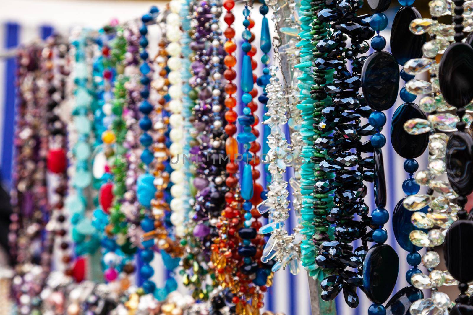 Various colorful beads in the market. Wallpaper background of a colorful necklace made of precious stones and colored beads. Semi-precious jewelry.