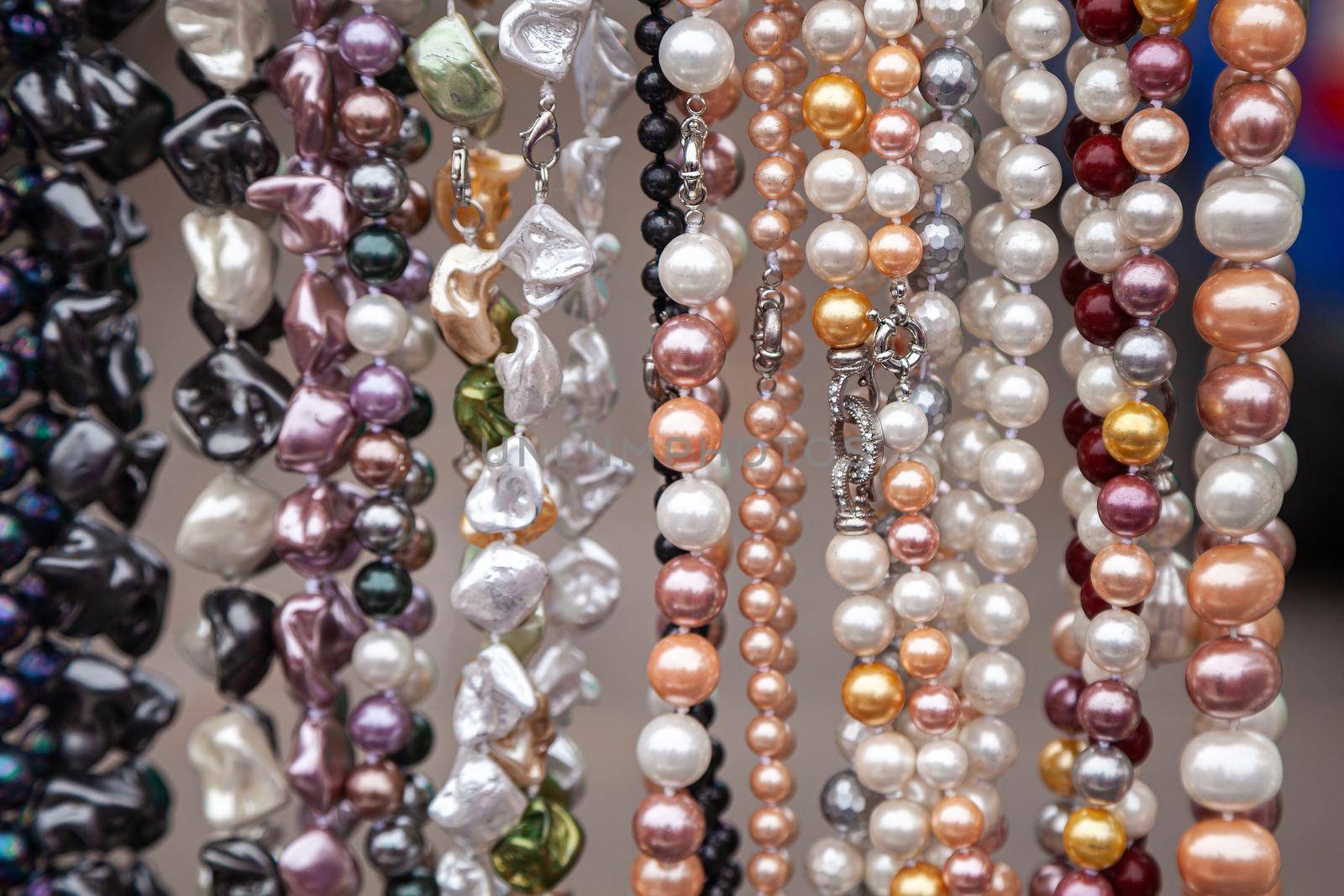 Various colorful beads in the market. Wallpaper background of a colorful necklace made of precious stones and colored beads. Semi-precious jewelry.