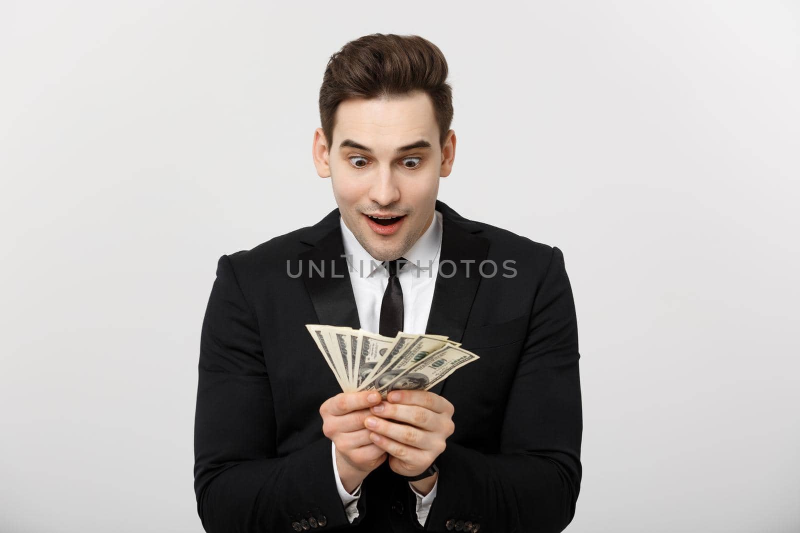 Business Concept: Portrait of shocked businessman showing a lot of money isolated over white background