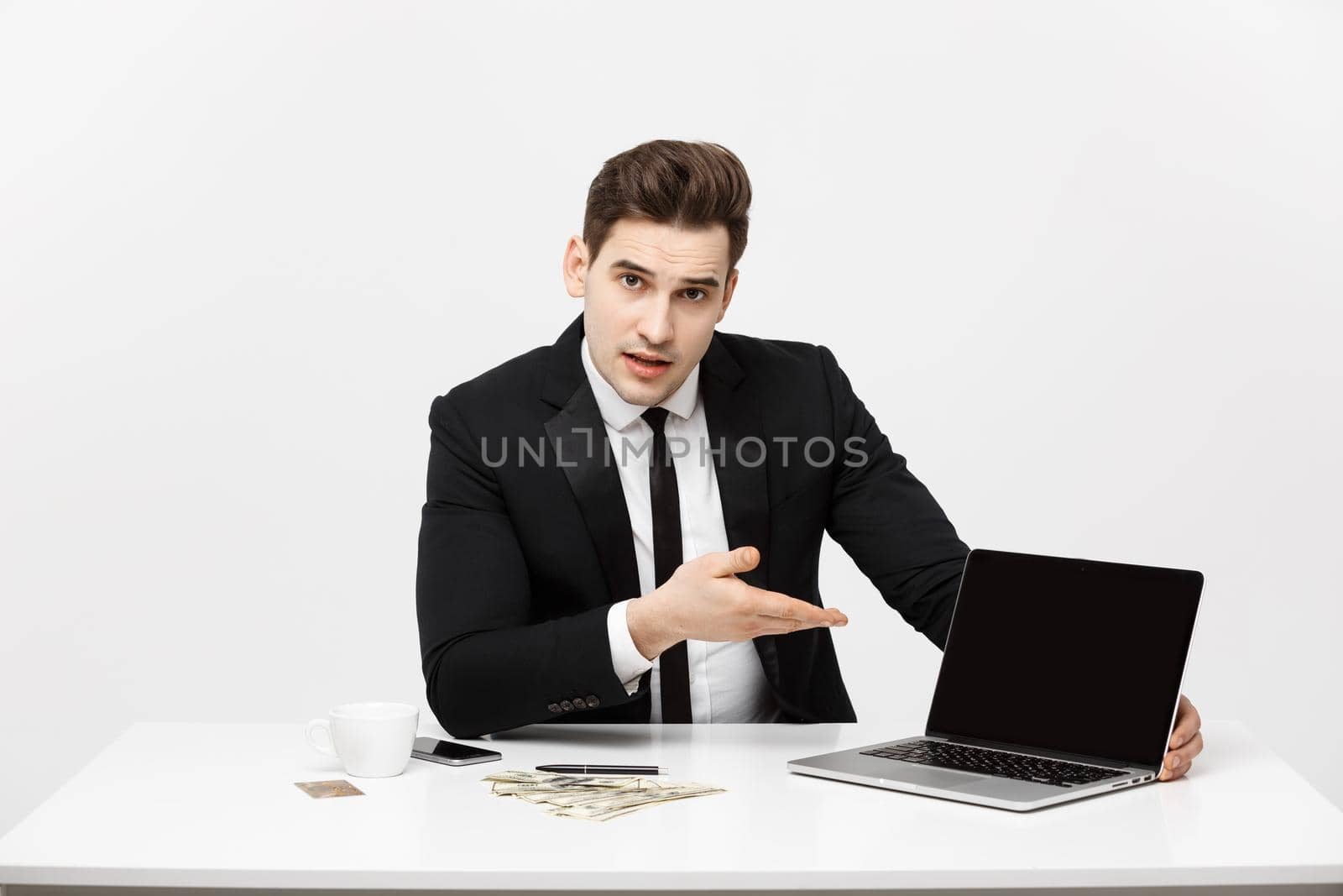 Smiling businessman presenting his laptop computer to the viewer with a blank screen with copy space.