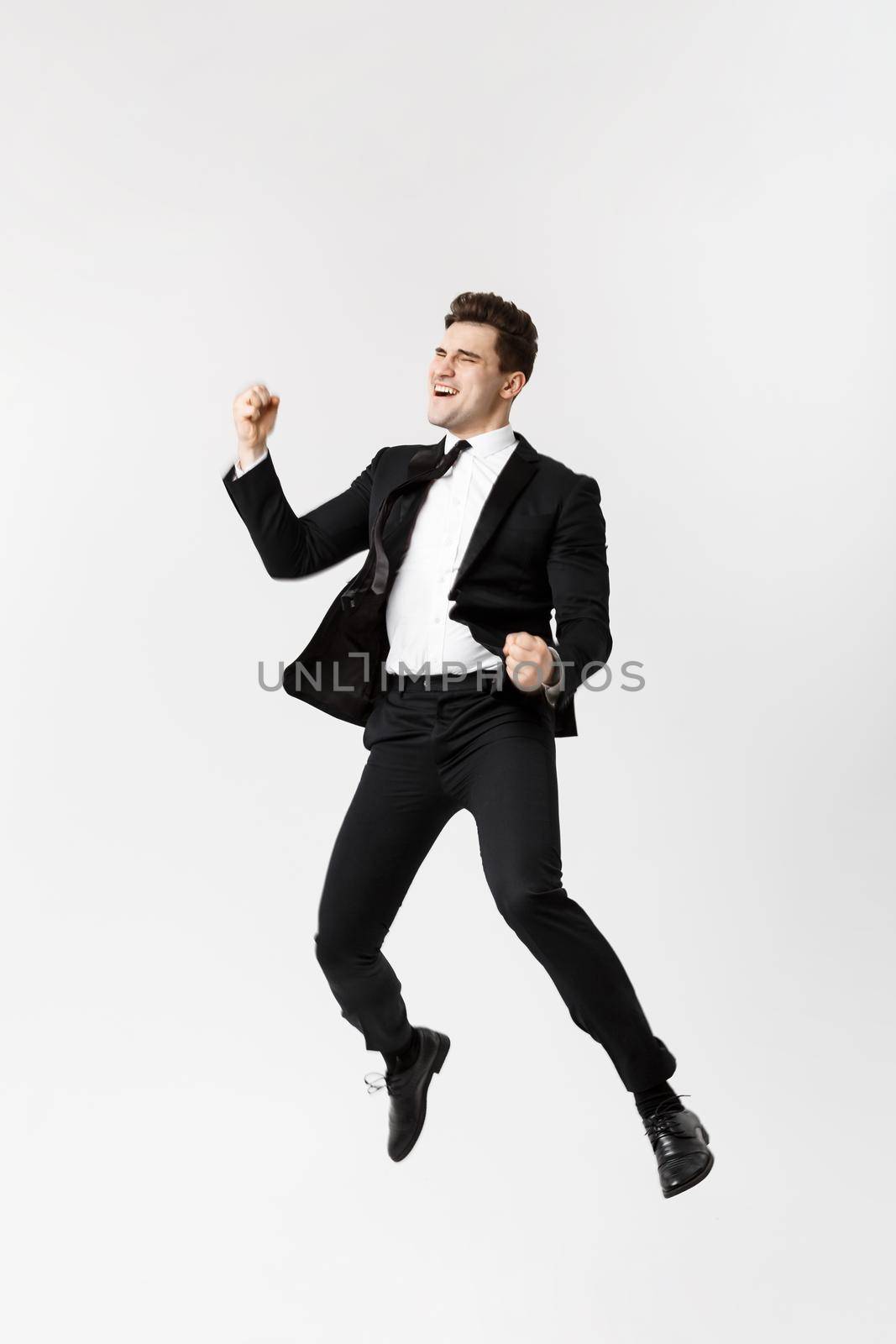 Full length Portrait Funny cheerful businessman jumping in air over gray background.