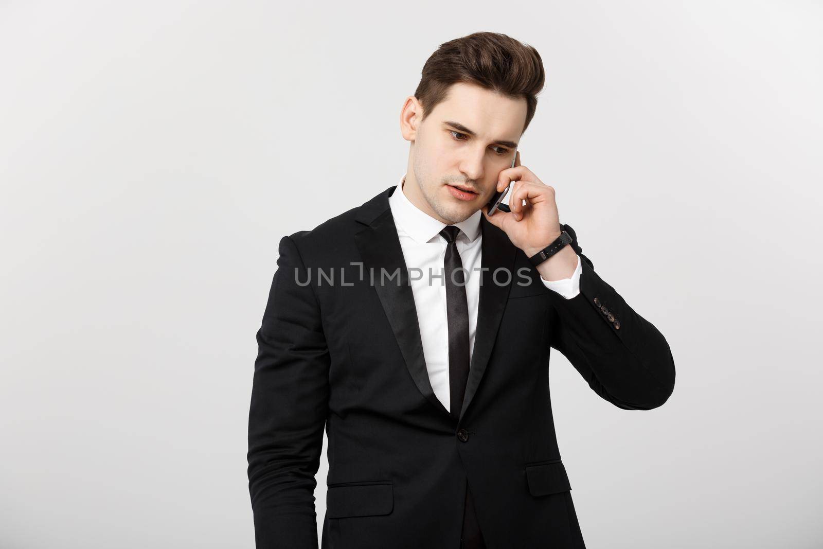 Business Concept: Portrait of young handsome businessman talking on mobile phone with serious and stress expression. Isolated over white background