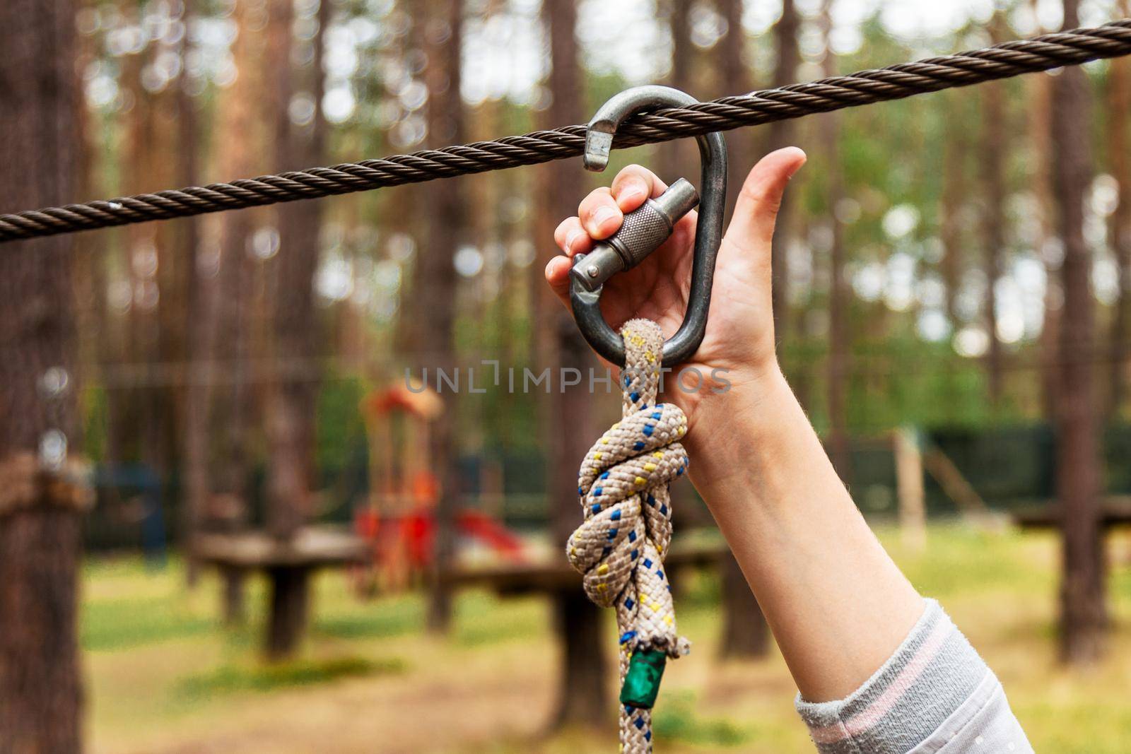 A child fastens a carbine on a safety rope.