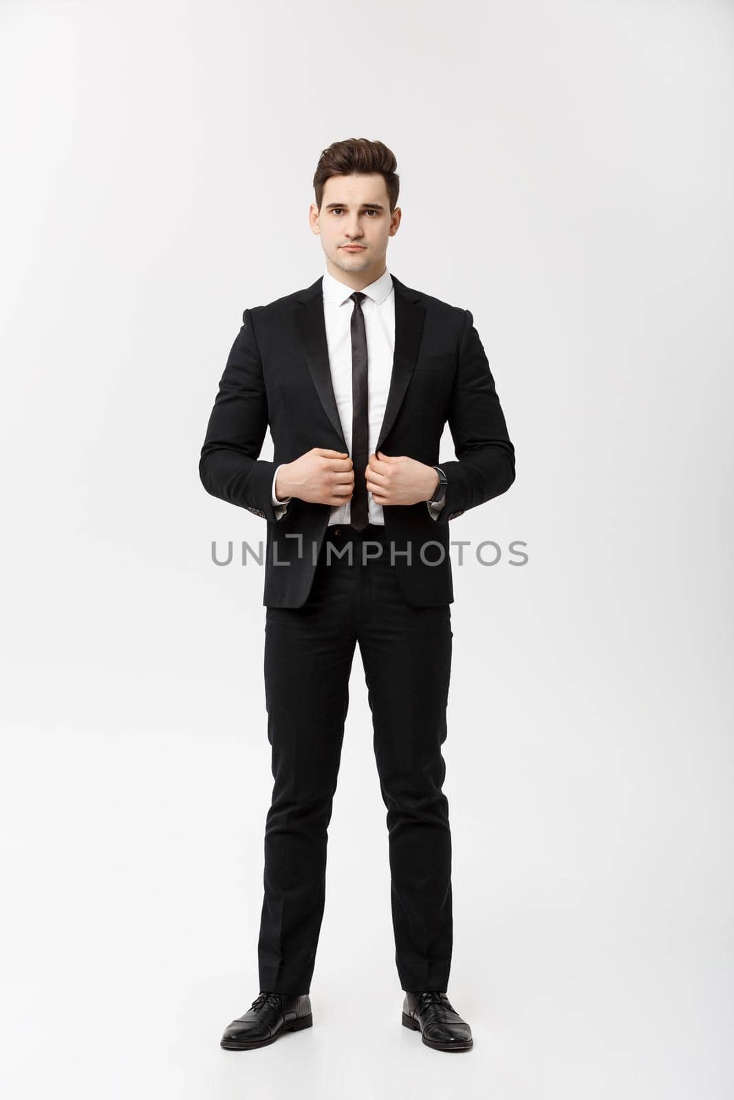 Business Concept: Handsome Man Happy Smile Young Handsome Guy in smart suit posing over Isolated Grey Background