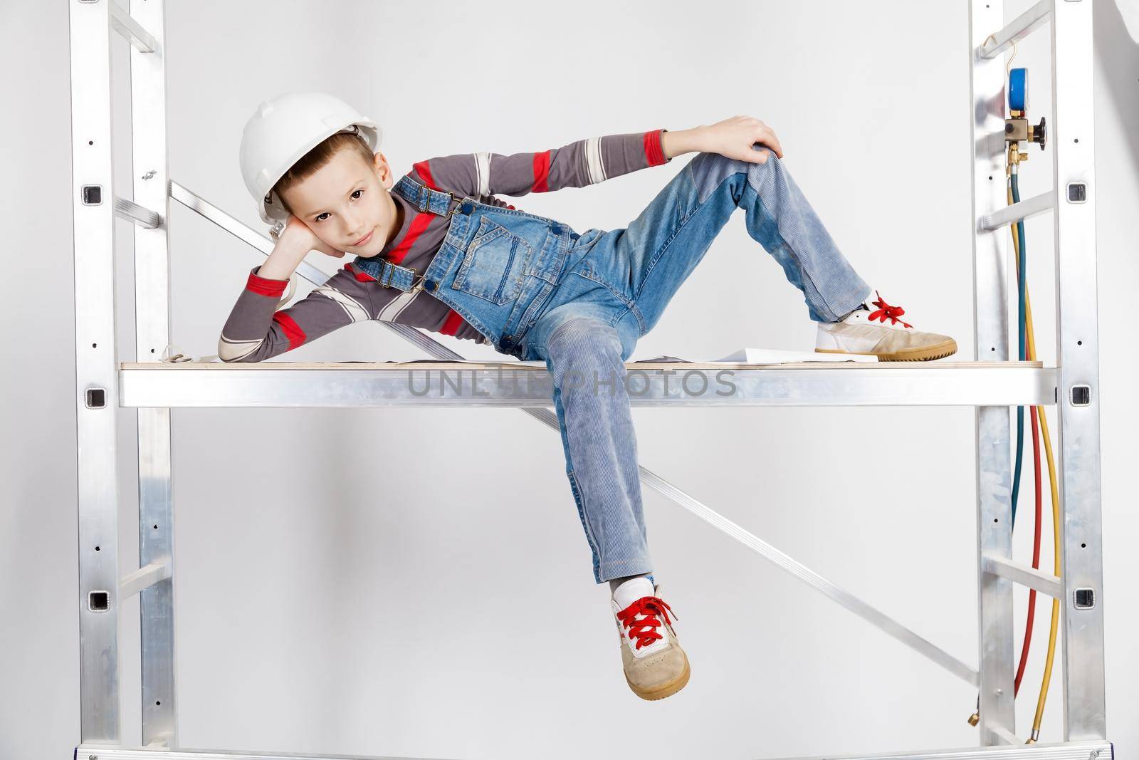Boy builder in a helmet lying on the scaffolds