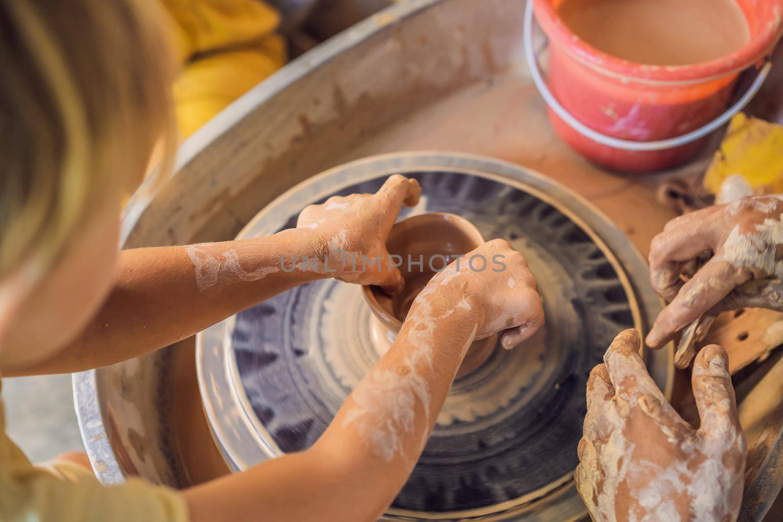 Father and son doing ceramic pot in pottery workshop by galitskaya