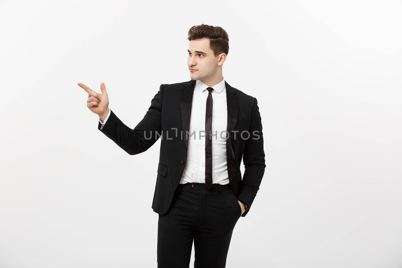 Business Concept: Close up portrait of young successful brunete stock-market broker guy or businessman pointing on a copyspace with his finger on white background