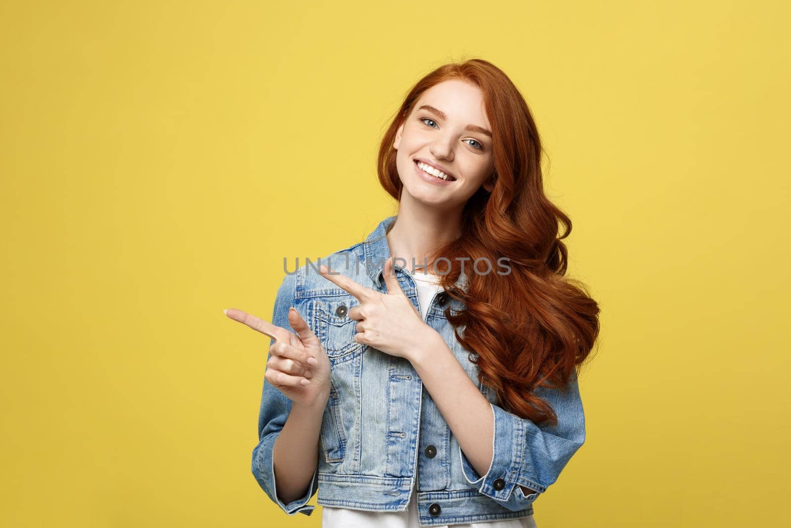 Lifestyle Concept: Happy excited cuacaisan tourist girl pointing finger on copy space isolated on golden yellow background.