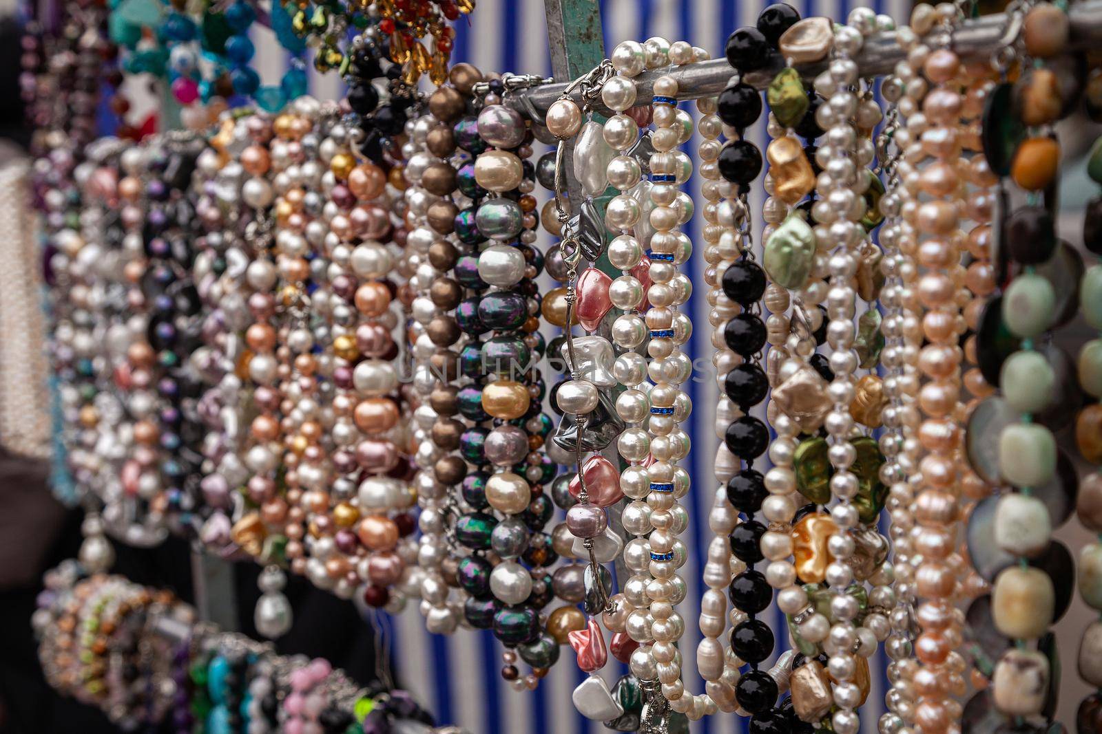 Various colorful beads in the market. Wallpaper background of a colorful necklace made of precious stones and colored beads. Semi-precious jewelry.