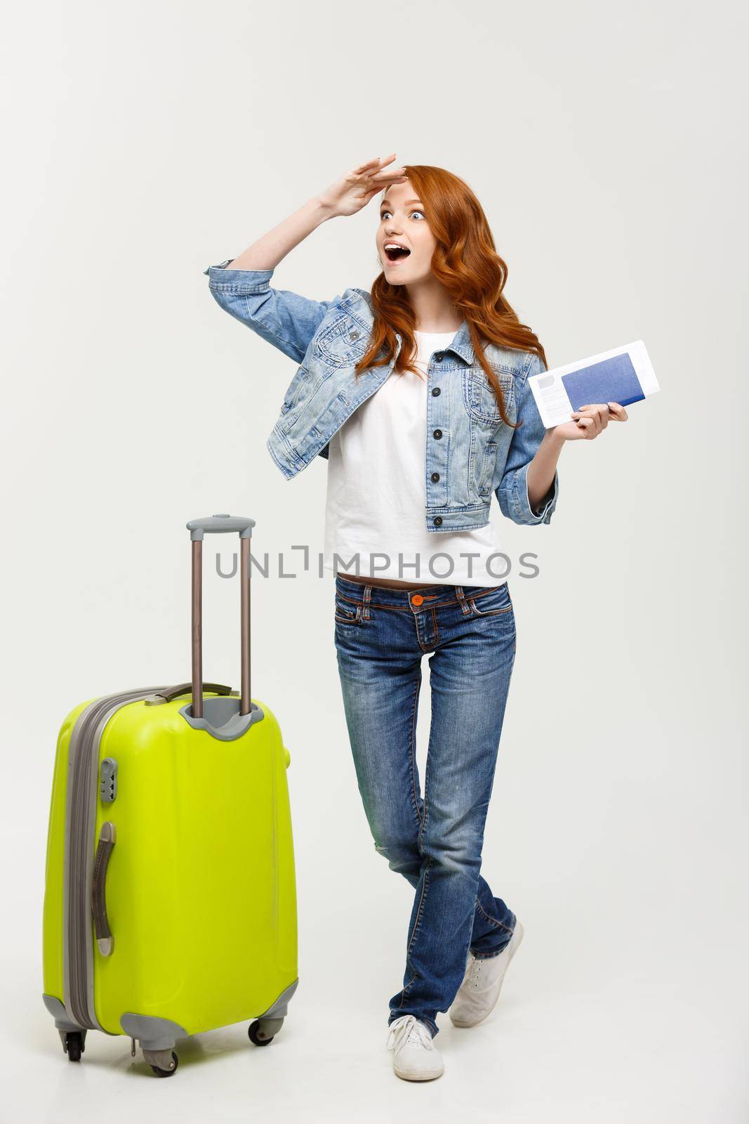 Travel Concept: Full-length young happy surprised beautiful woman holding green suitcase over white background.