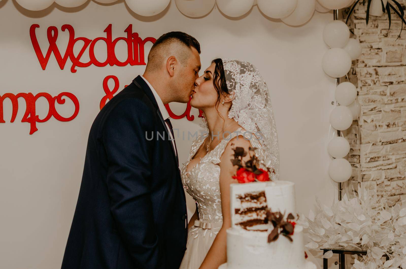 groom and bride at wedding cut their large multi-tiered white cake taste it fed from each other. by AndriiDrachuk