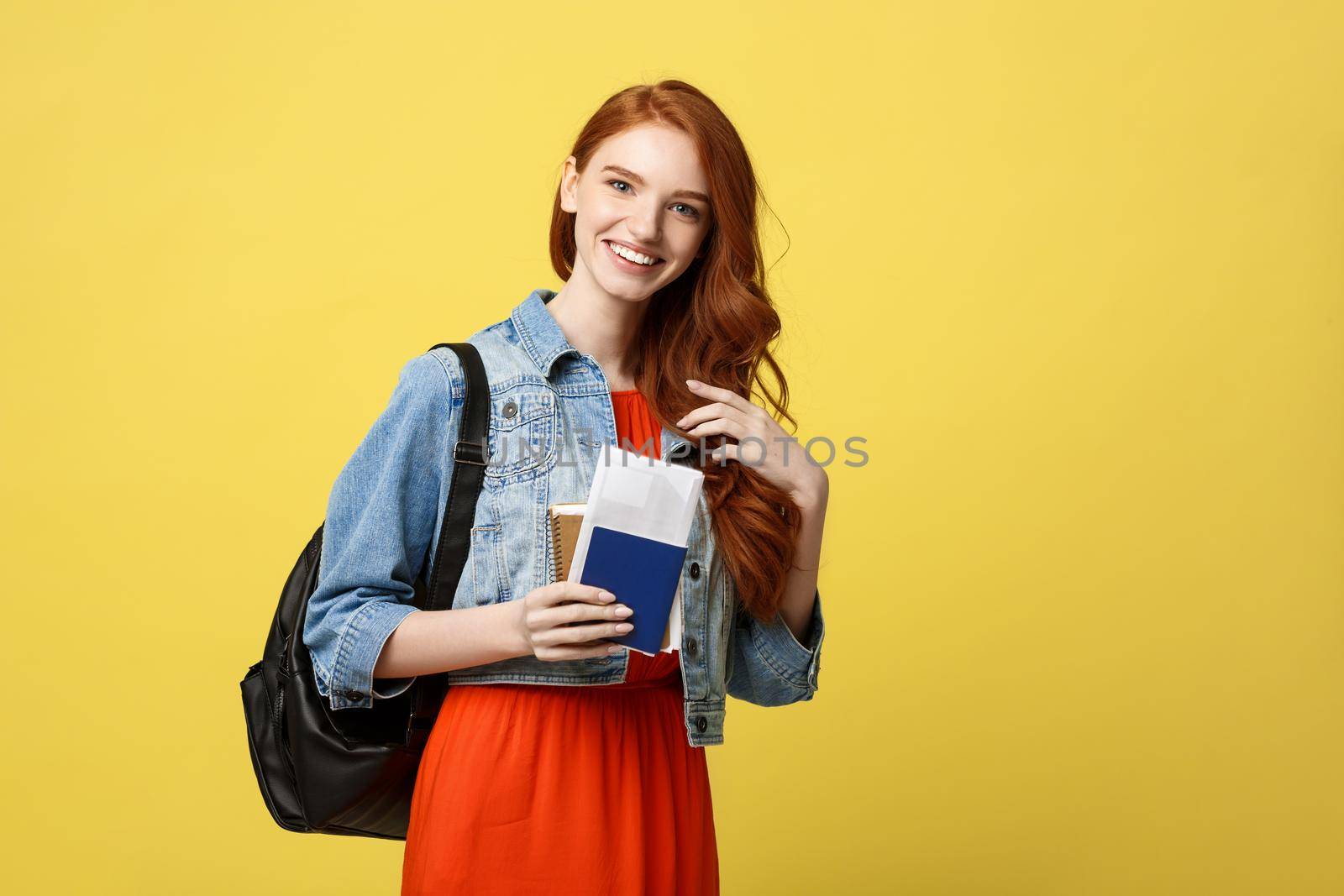 Travel and Lifestyle concept: Full length studio portrait of pretty young student woman holding passport with tickets. Isolated on bright yellow background