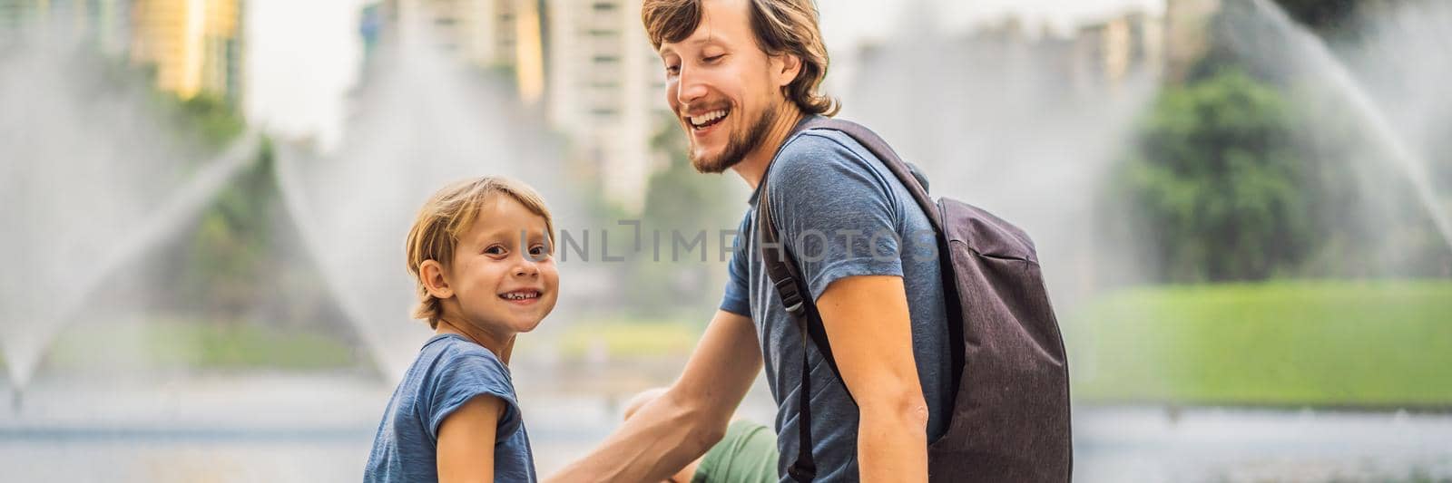 Dad and son tourists on background of fountain on the lake at night, near by Twin Towers with city on background. Kuala Lumpur, Malaysia BANNER, LONG FORMAT by galitskaya