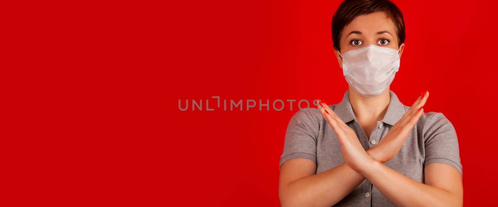 A woman in a mask indicates stopping the spread of the COVID-19 virus. The concept of preventing the spread of the epidemic and treating coronavirus. Coronavirus treatment.