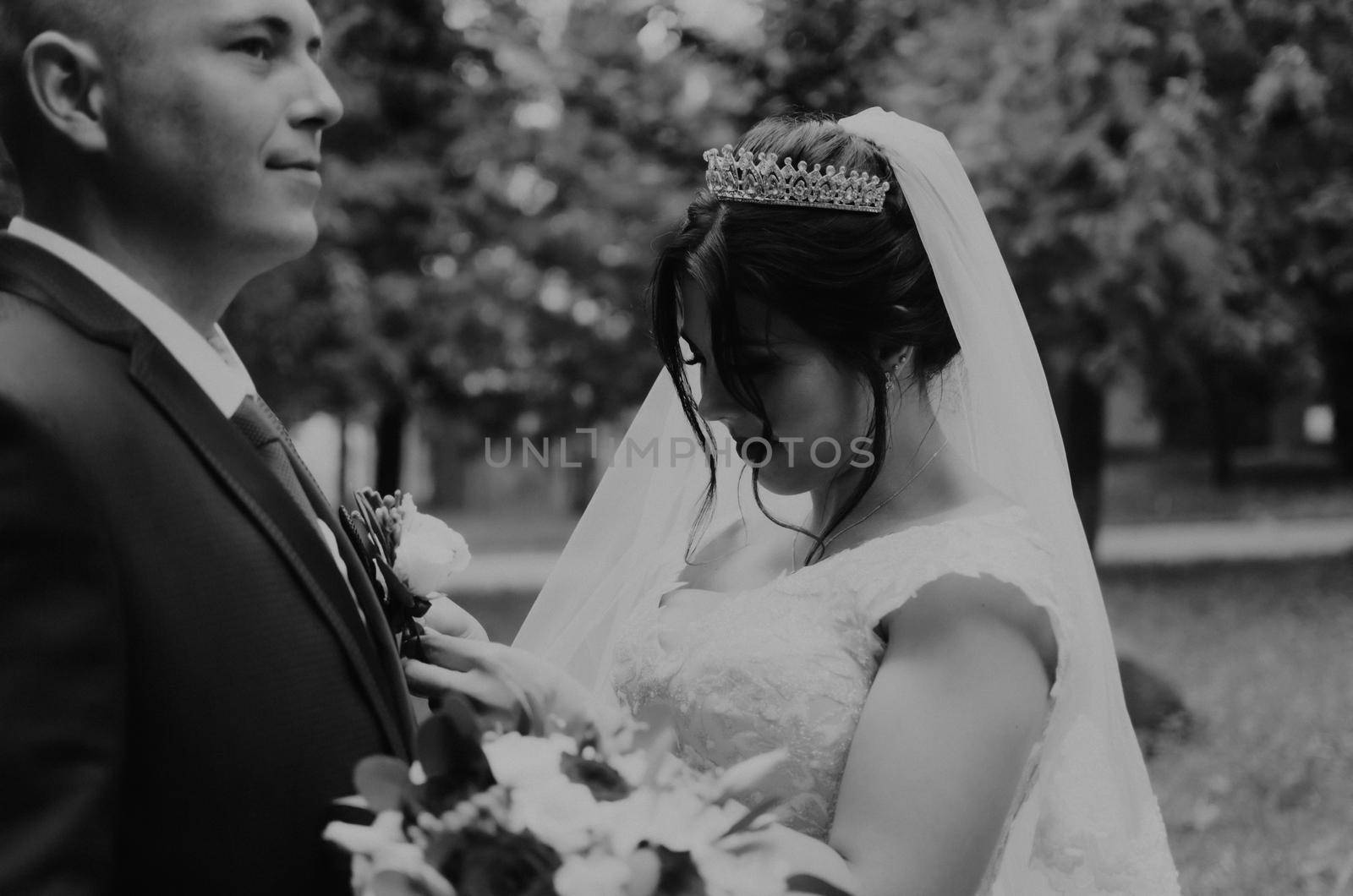 blonde European Caucasian young man groom in blue suit and black-haired woman bride in white wedding dress with long veil and tiara on head. first meeting newlyweds groom wait sees bride