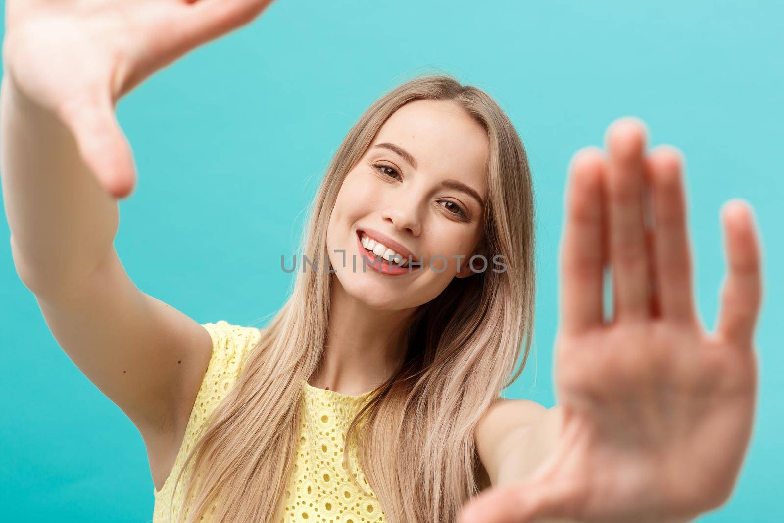 Close-up Young Caucasian woman face and eye care and she making frame with hands isolated over pastel blue background