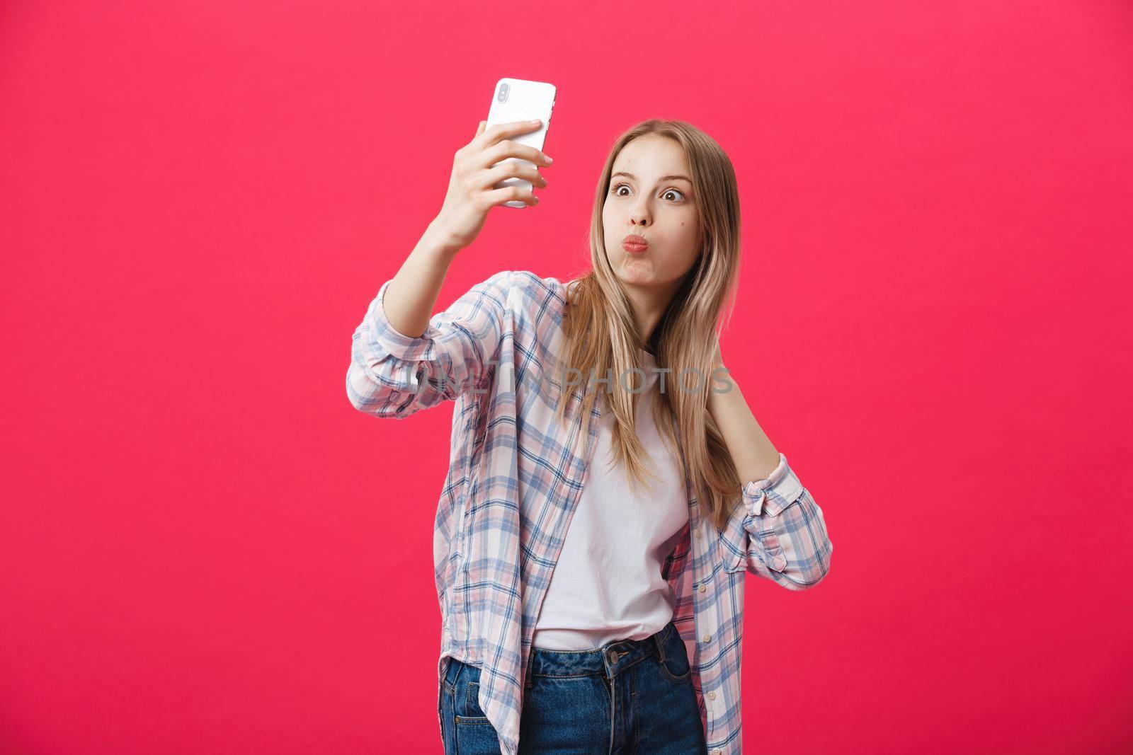 Charming young woman in white hat travel and take selfie on front camera smartphone posing isolated on shine pink background by Benzoix