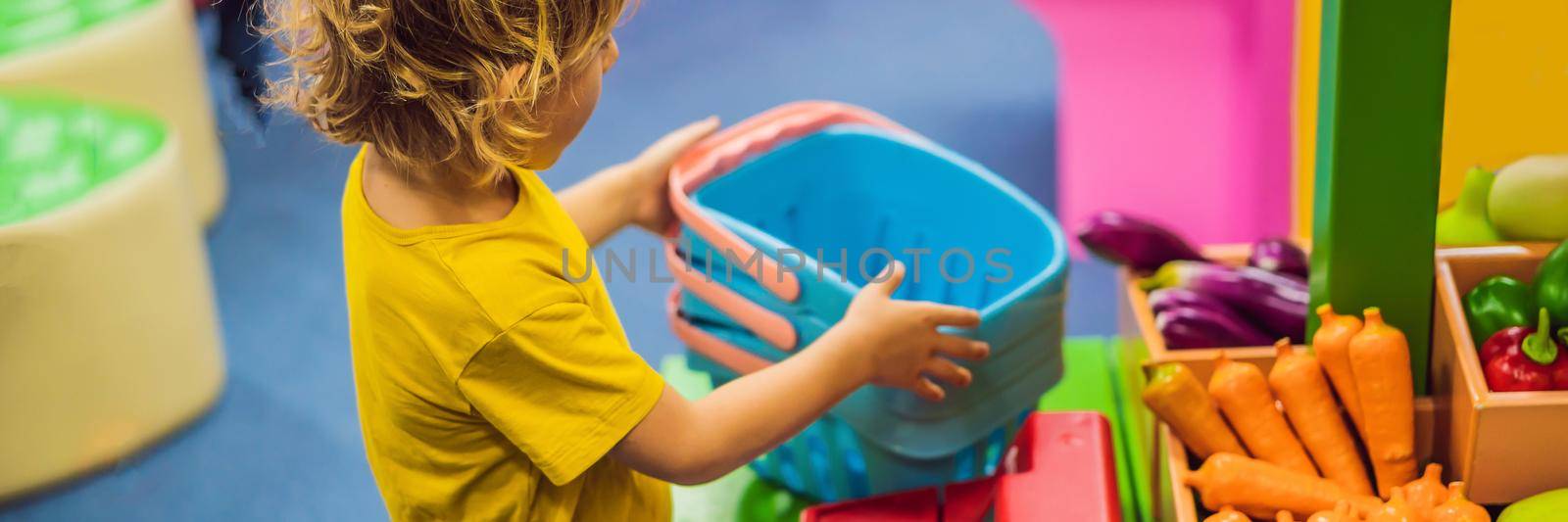 Boy shopping fruits and vegetables in a toy supermarket. BANNER, LONG FORMAT