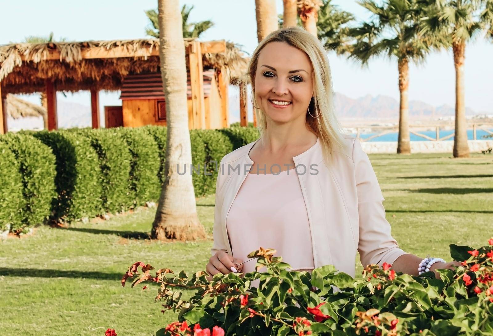 Blonde girl wearing pink clothes Against the background of palm trees and the sea. Enjoys vacation in Egypt.