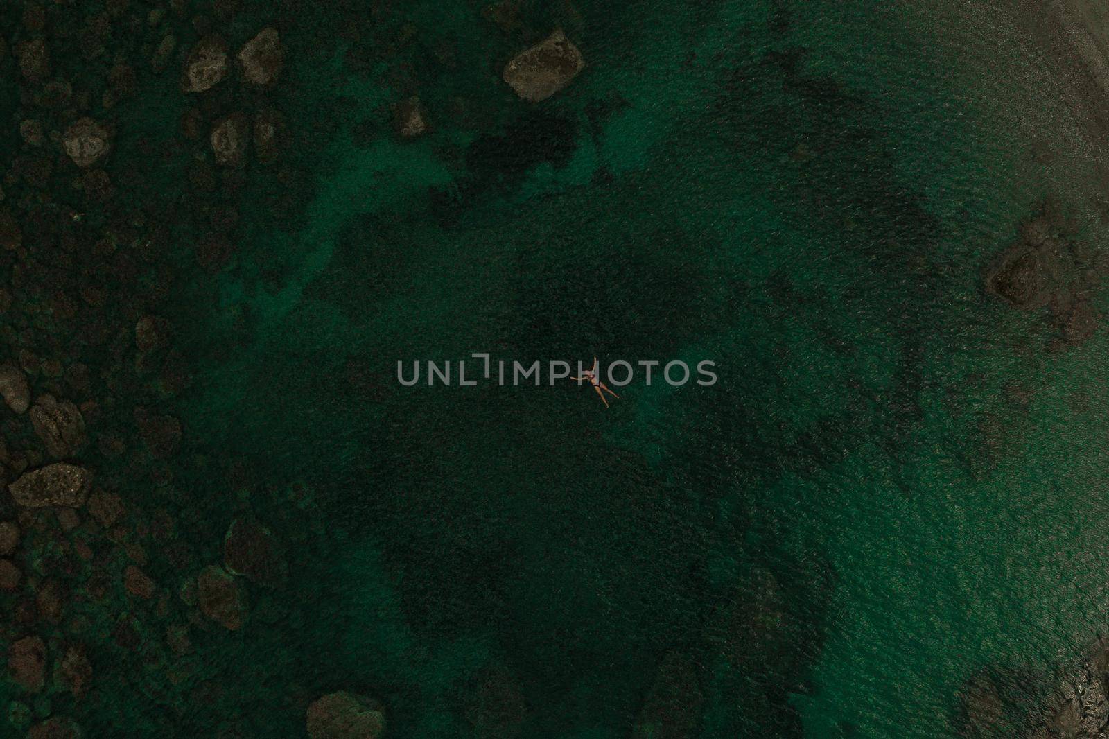 Aerial top nature view above green turquoise Adriatic sea in Albania. Beautiful young woman swimming alone in middle ocean water. girl in swimsuit bikini lying. wide panoramic view marine. summer