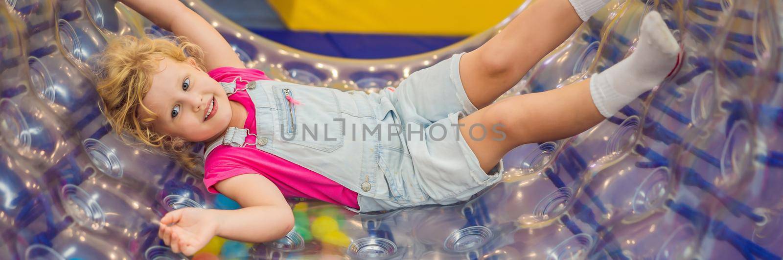 Cute little boy and girl playing in Zorb a rolling plastic cylinder ring with a hole in the middle, intdoor BANNER, LONG FORMAT by galitskaya