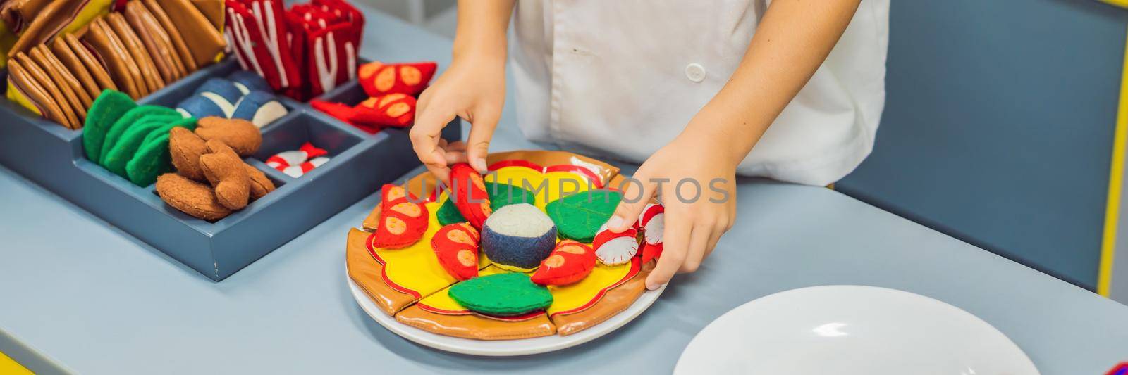 The boy plays in the toy kitchen, cooks a pizza. BANNER, LONG FORMAT