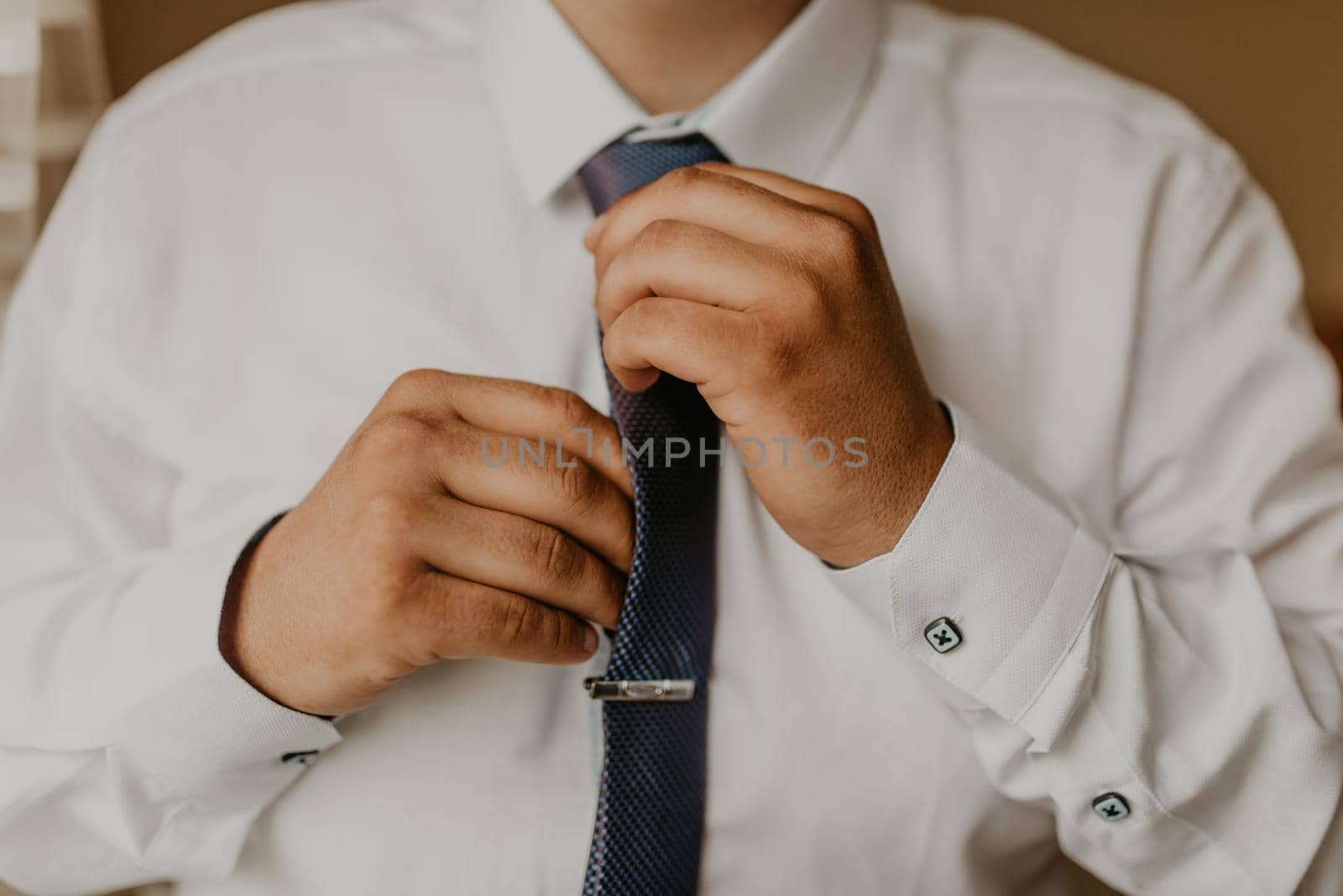 blonde European Caucasian young groom in shirt business suit with tie prepare for wedding. a man preparing for an important event a meeting indoors worries