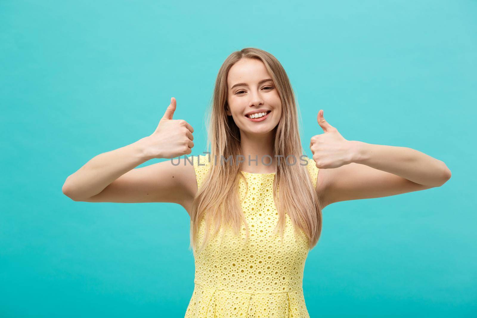 Success and Lifestyle Concept: Young happy cheerful woman showing thumb up over pastel blue background