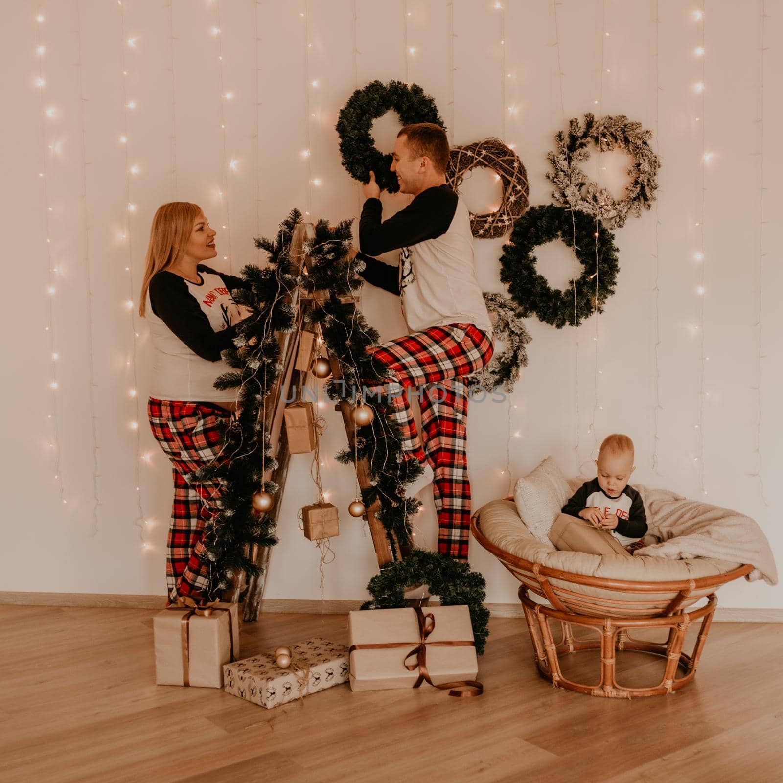 family with pregnant wife on stepladder decorates the house for the New Year little baby girl sitting in a chair and playing. Christmas morning. New Year's interior.Valentine's Day celebration