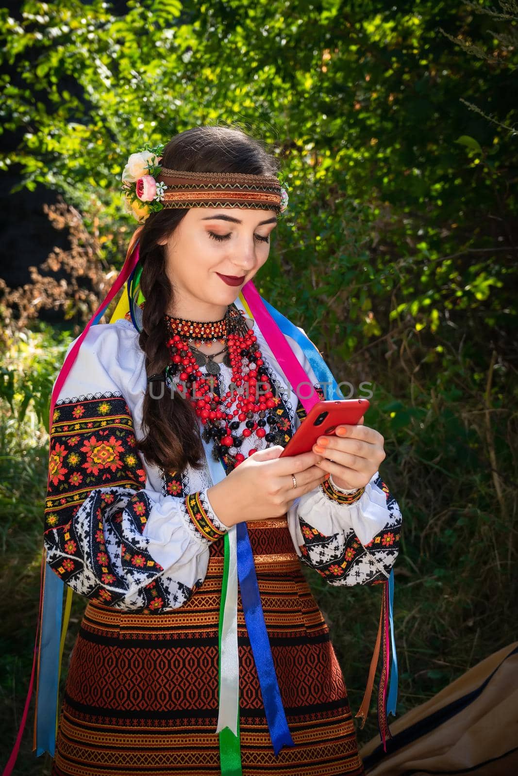 Ukrainian woman in an embroidered shirt holds a mobile phone in her hands by Serhii_Voroshchuk