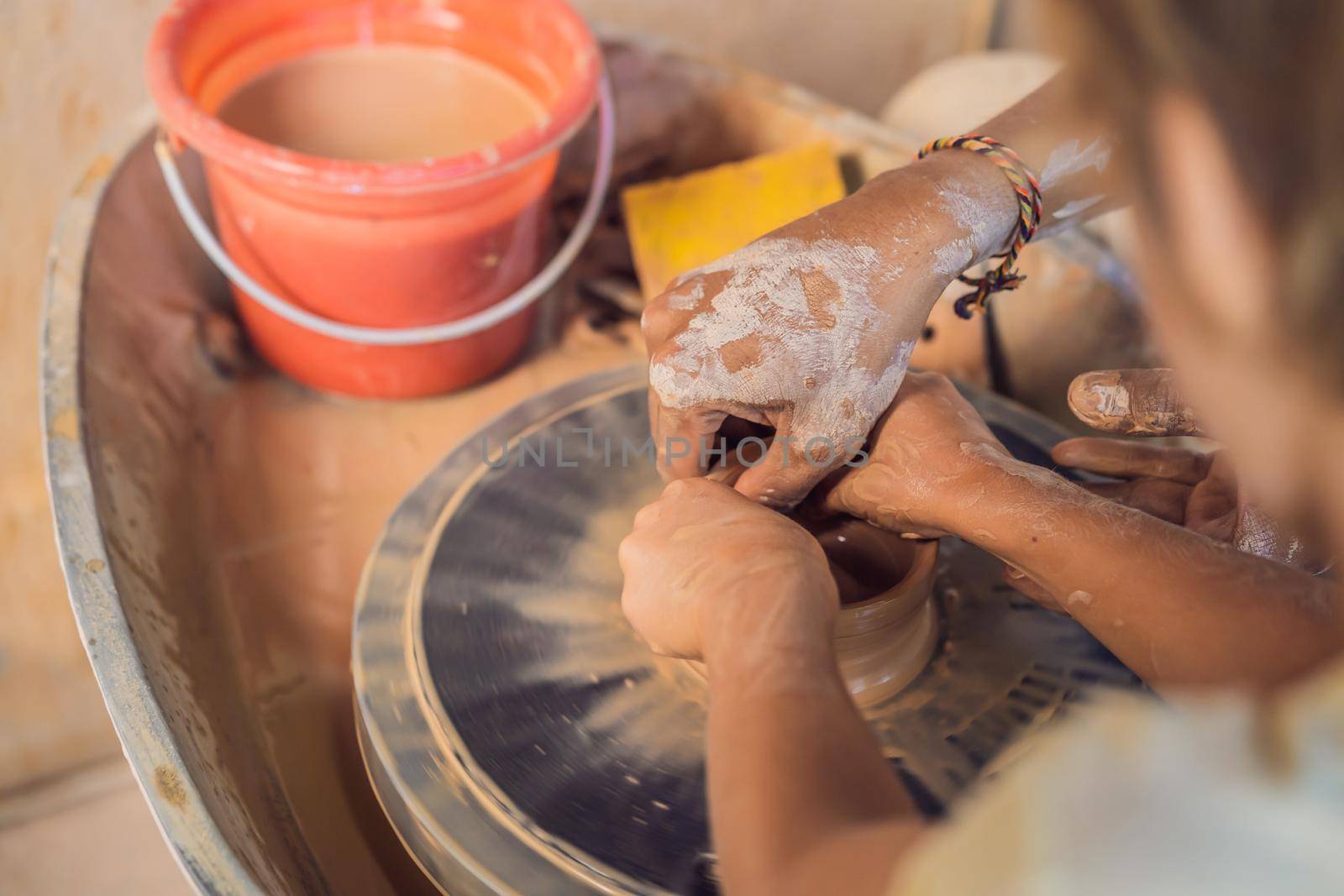 Father and son doing ceramic pot in pottery workshop by galitskaya