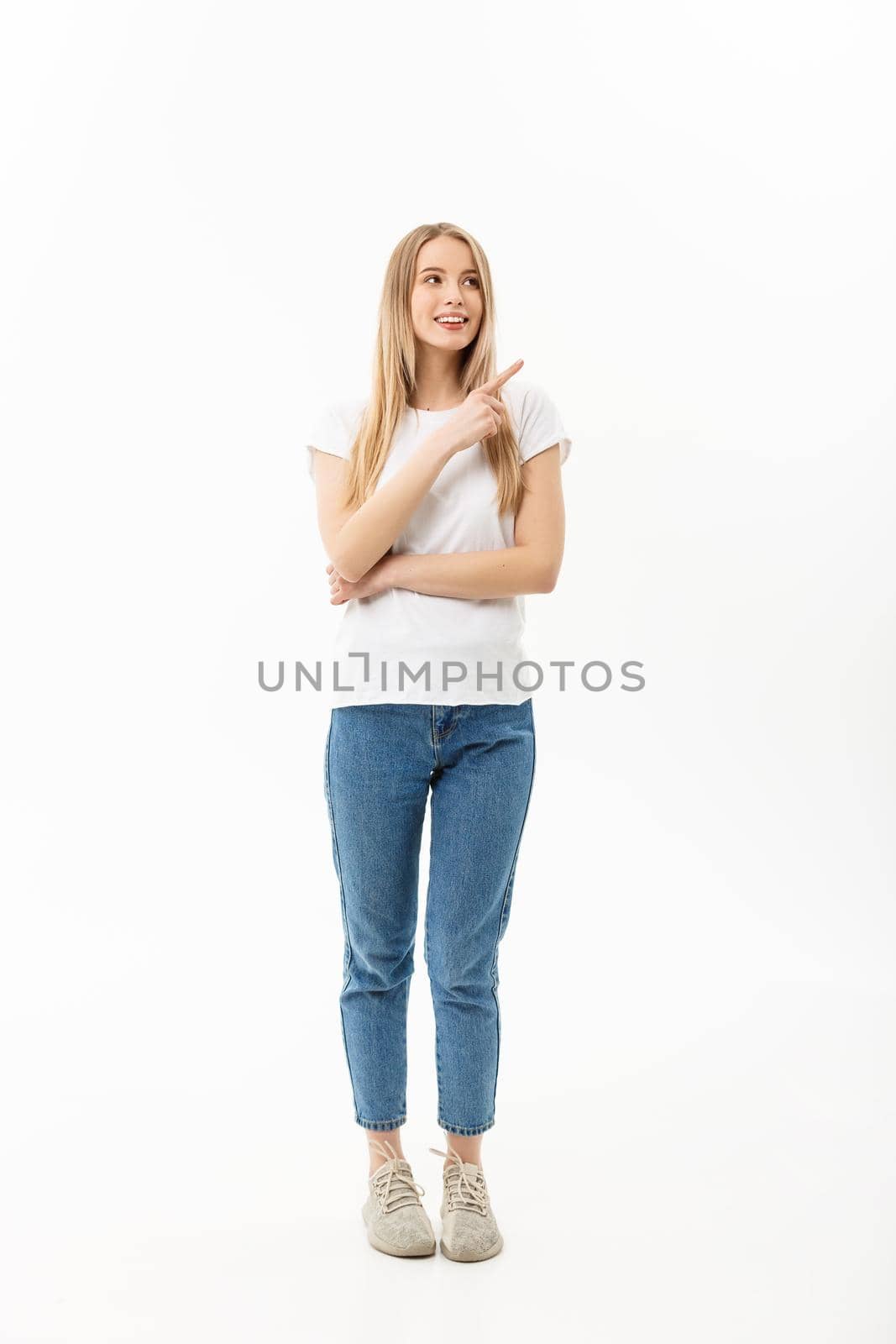 Young attractive happy woman in casual cloth pointing at white copy space background.