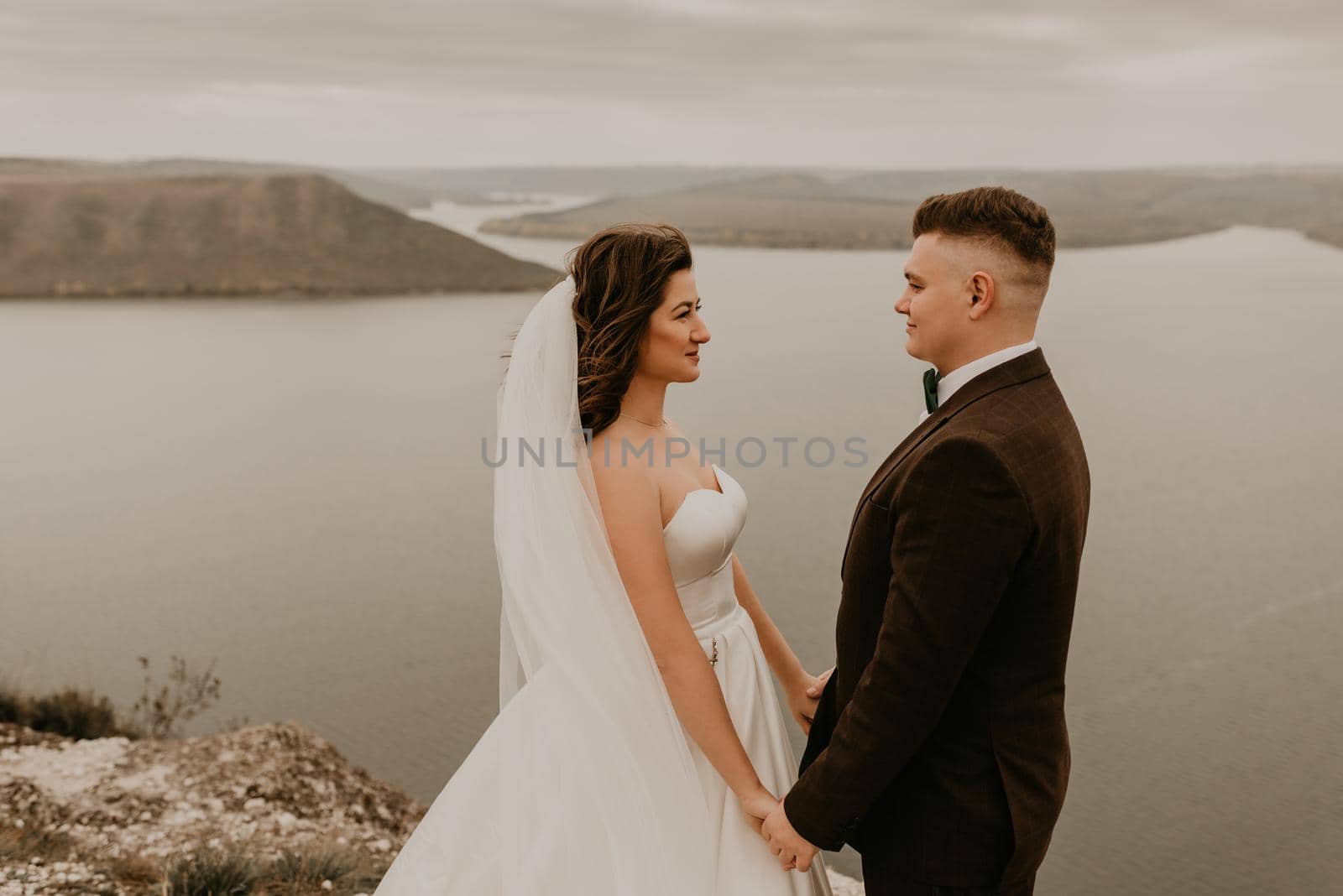 couple wedding bride groom man and woman on rocks above cliff by AndriiDrachuk