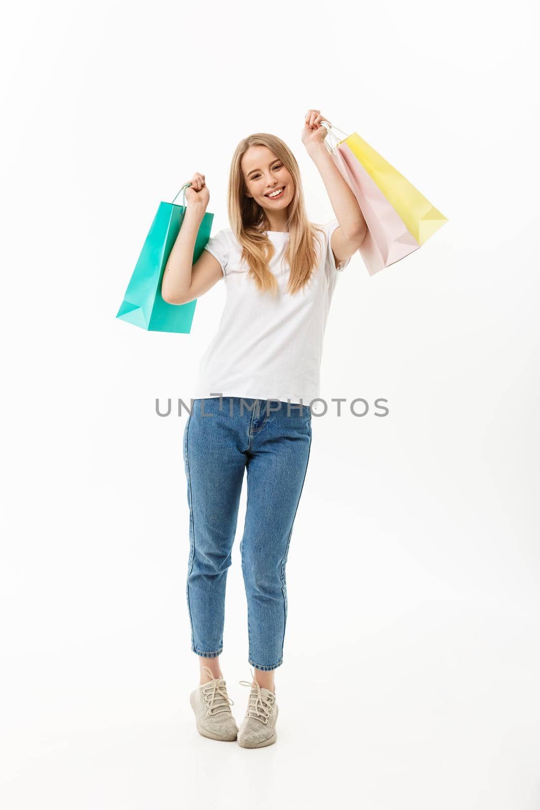 Full length portrait of a beautiful young woman posing with shopping bags, isolated on white background.