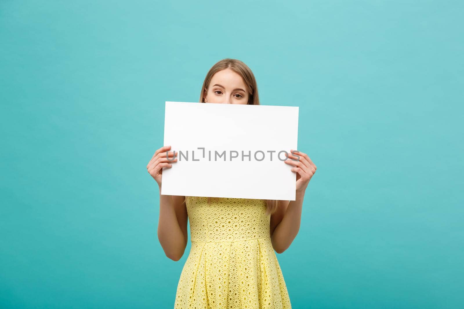 Beautiful woman holding a blank billboard isolated on blue background.