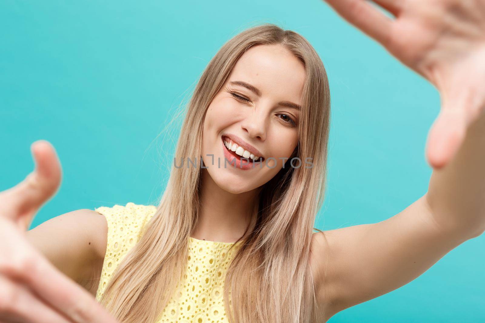 Close-up Young Caucasian woman face and eye care and she making frame with hands isolated over pastel blue background