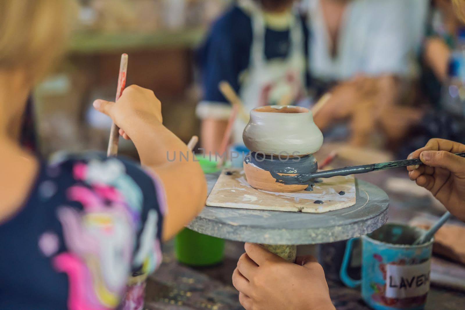 mother and son doing ceramic pot in pottery workshop by galitskaya