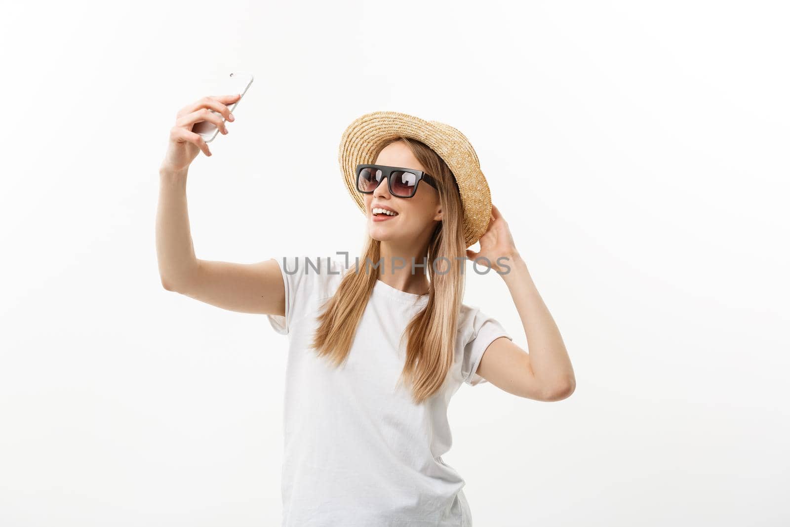 Fashion and Lifestyle Concept: pretty young woman wearing a hat, sunglasses takeing a photo of herself by mobile phone isolated over white background by Benzoix