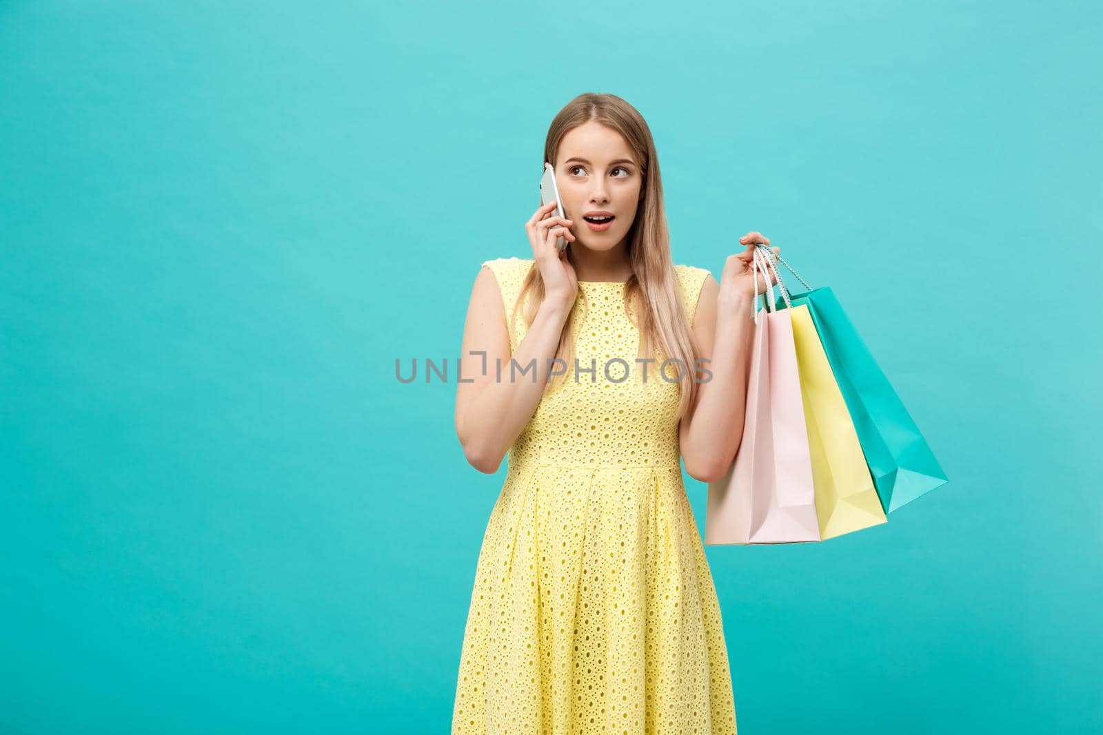 Portrait of happy fashion caucasian woman with shopping bags calling on mobile phone. Isolated on blue background