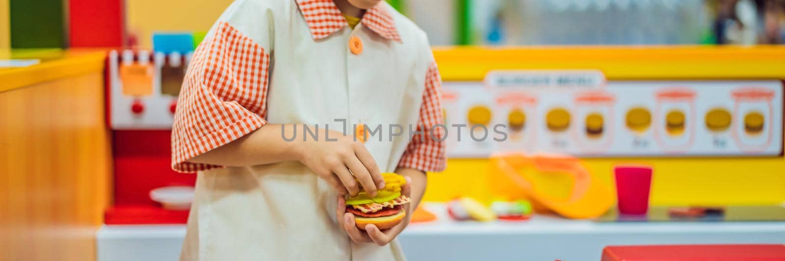 The boy plays in the toy kitchen, cooks a hamburger BANNER, LONG FORMAT by galitskaya