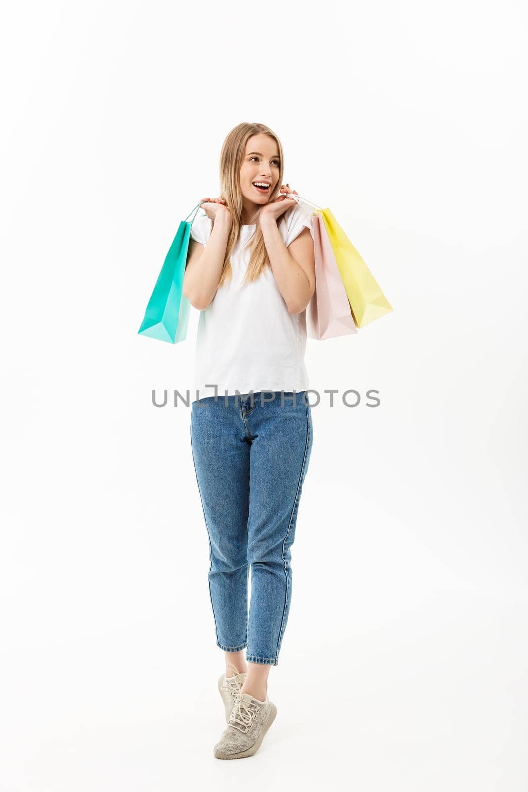 Full length portrait of a beautiful young woman posing with shopping bags, isolated on white background.