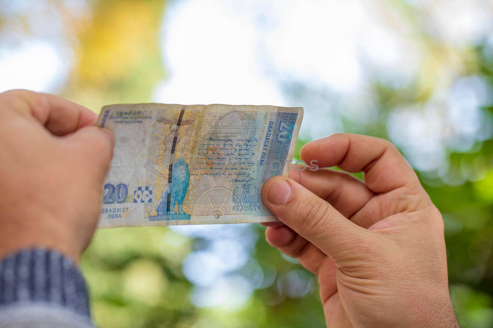 Checking counterfeit money with light. Money against the lights in hands. Check for the watermark of currency.