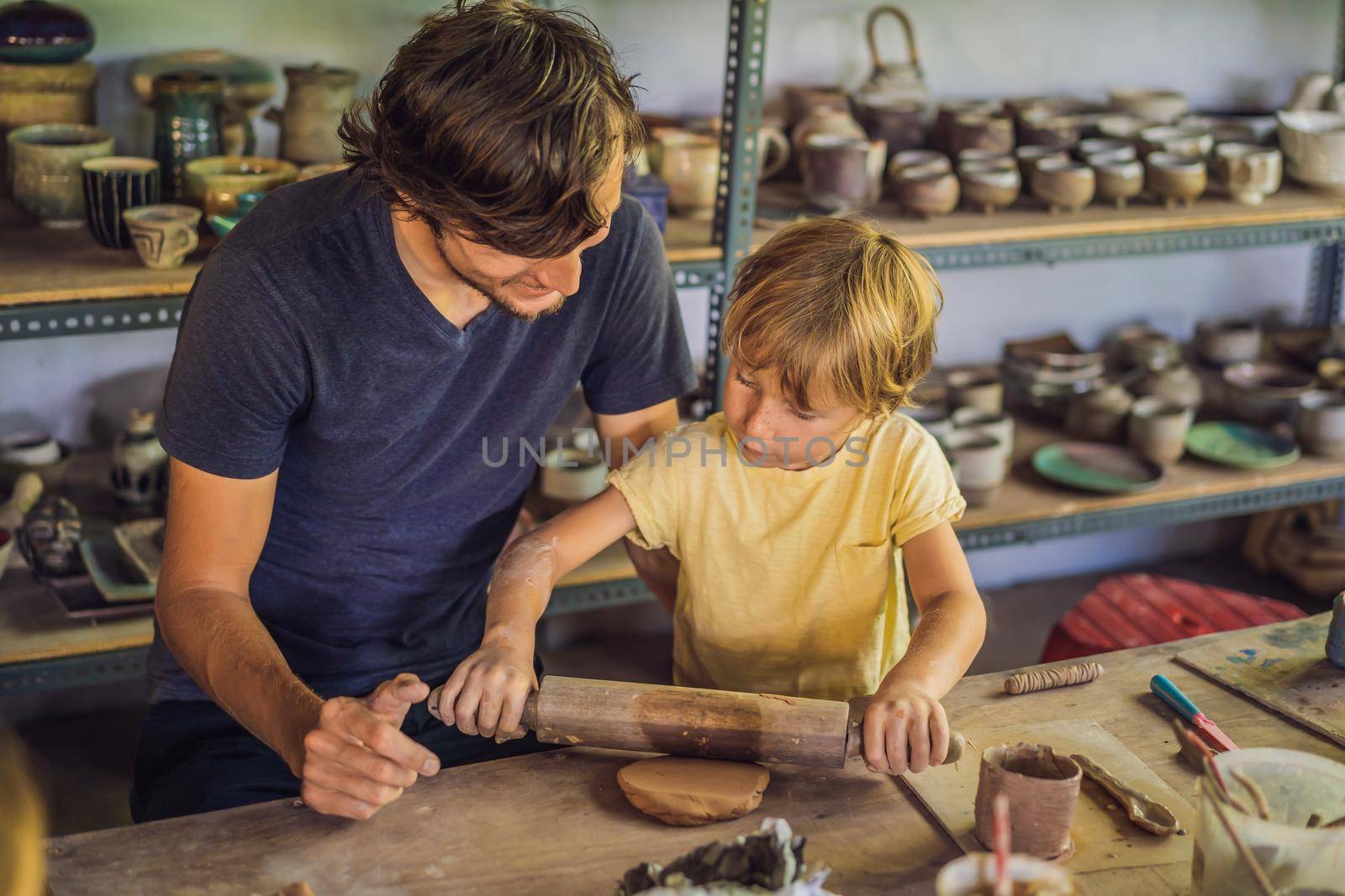 Father and son doing ceramic pot in pottery workshop by galitskaya