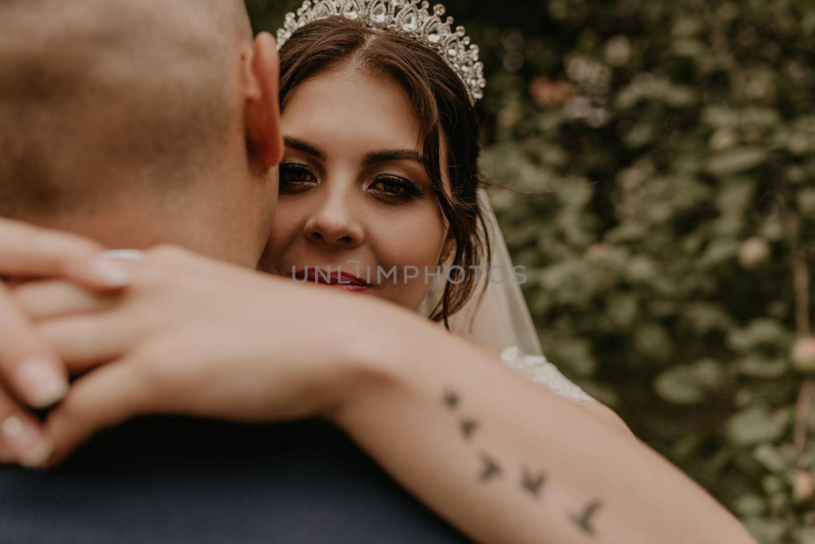 bride hugs groom arm tattoo in the form of flying birds swallows by AndriiDrachuk