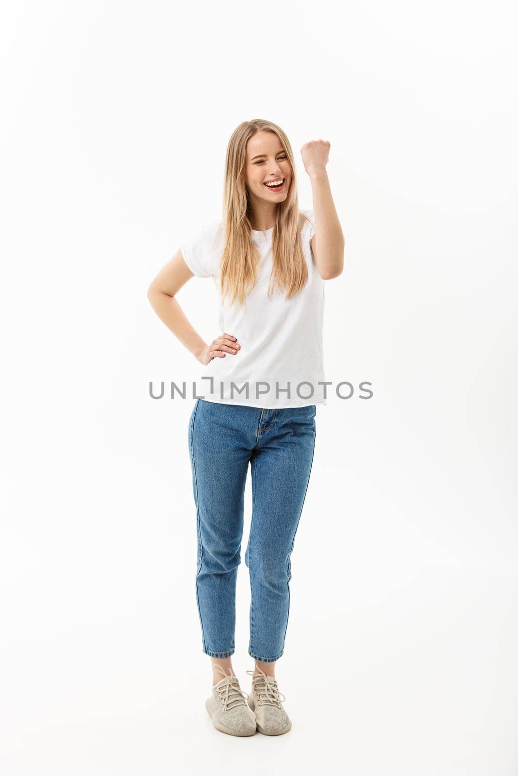 Full-length Portrait of a cheerful woman in white shirt and jean celebrating her success over white background.