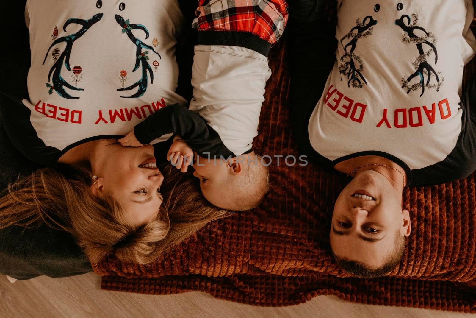 cheerful happy family in pajamas with a child lie on bed in the bedroom. new year family clothes looks outfits. Valentine's Day Celebration Gifts